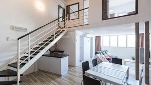A modern apartment with a staircase, a dining area, and a living space with a sofa and TV. - 3-Bed Exec Suite RumahKu Airport Penang (Bayan Lepas)