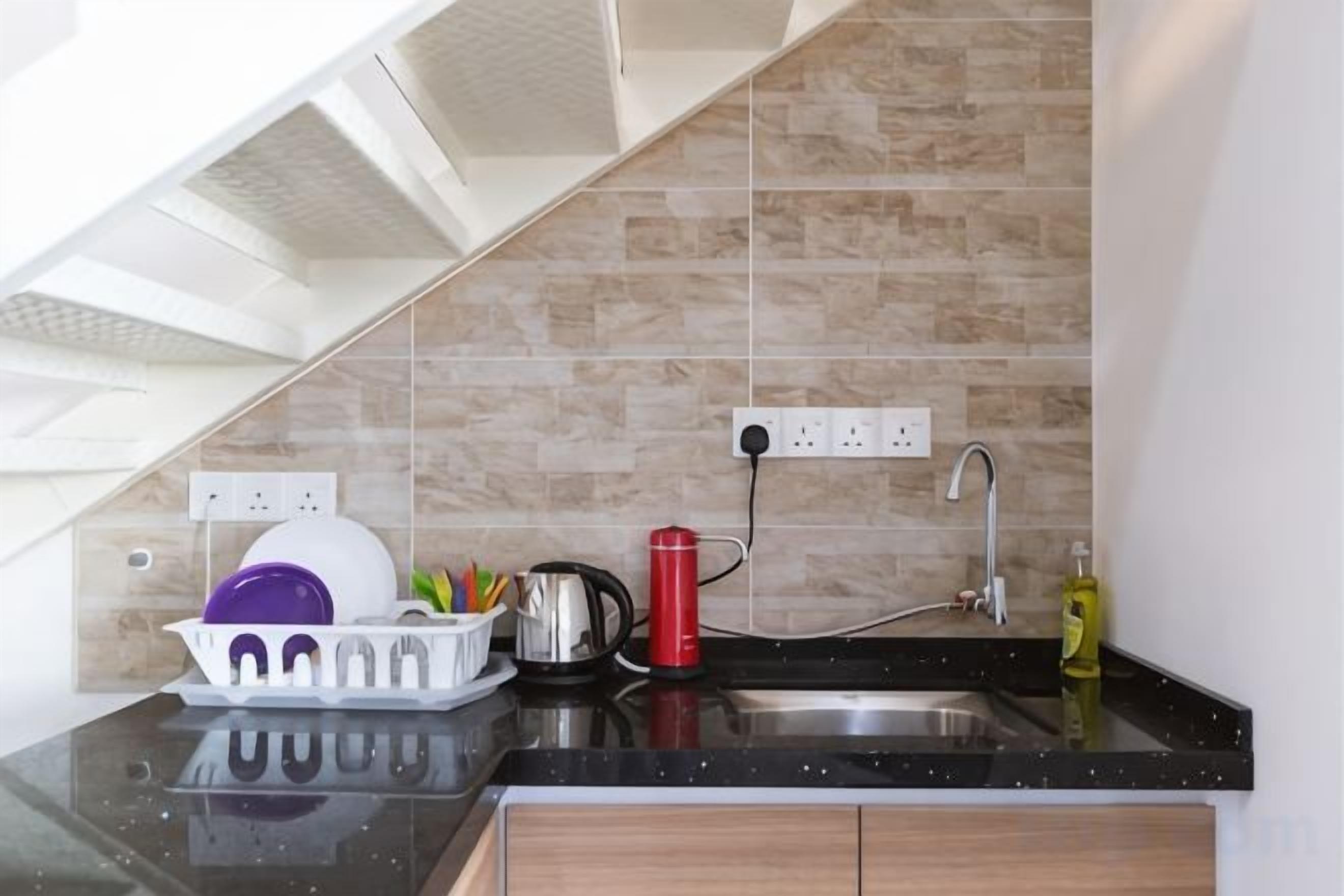 A kitchen with a black countertop, a sink, and a tiled backsplash.