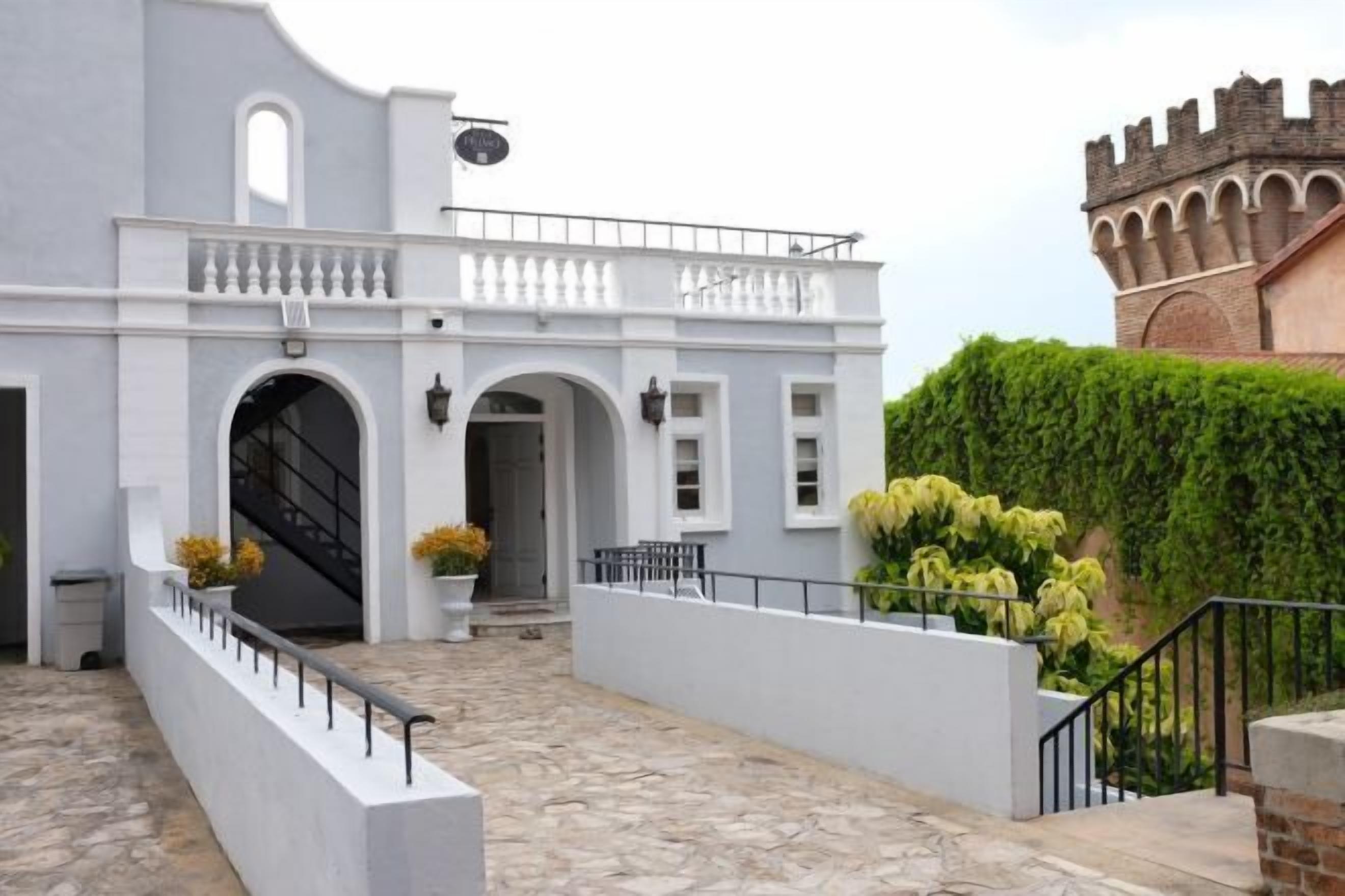 Un edificio con fachada blanca, un balcón y una escalera que lleva a una puerta.