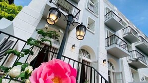 Ein mehrstöckiges Gebäude mit Balkonen, einer Blume im Vordergrund und einer Straßenlaterne.