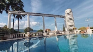 Ein klares, blaues Schwimmbecken mit dem Spiegelbild eines hohen Gebäudes und Palmen.