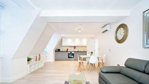 Ein modernes Wohnzimmer mit einer Eckcouch, einem Glastisch und einem Essbereich mit einem weißen Tisch und Stühlen.