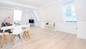 Un amplio salón con una mesa de comedor, sillas, un televisor y un ventanal grande.