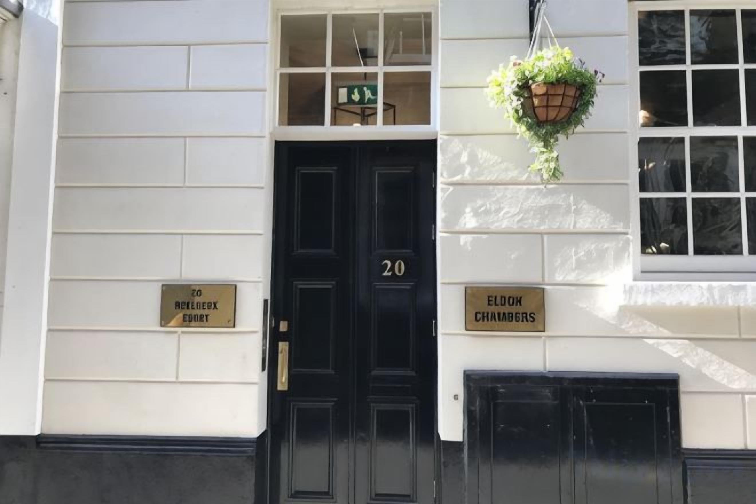 A building entrance with a black door marked '20', two signs reading 'ELOK CHURCHES' and 'ELOK REEDGROVE', and a hanging plant.