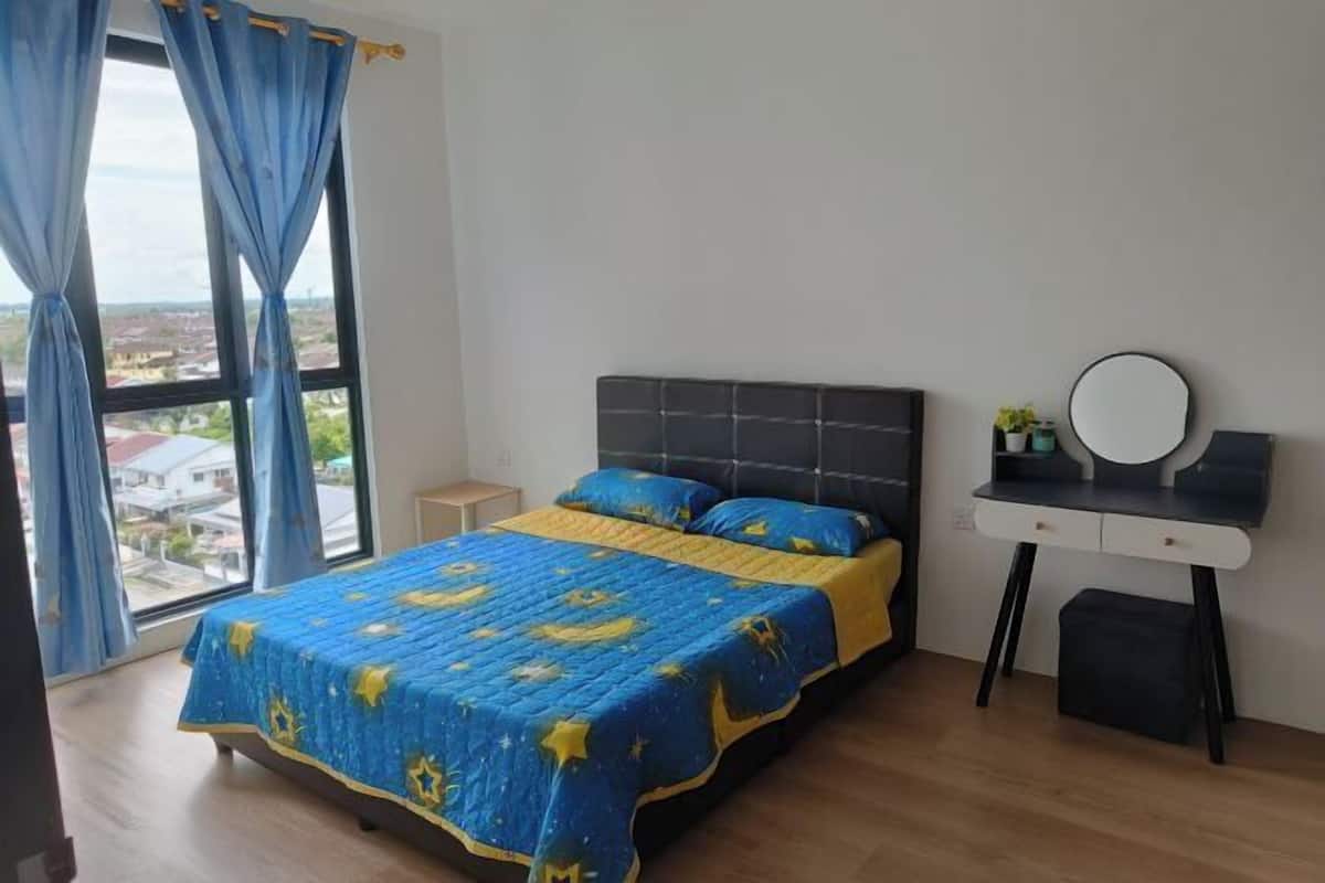 A bedroom with a bed, a bedside table, a mirror, and a view of the city through large windows.