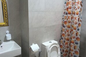 A bathroom with a sink, toilet, and a shower curtain with a sea shell pattern. - LittleChing @ Armadale Residence Galacity (Kuching)