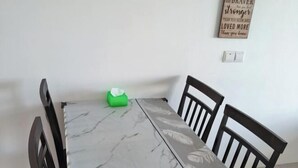 A dining table with a marble pattern, surrounded by four wooden chairs. A green tissue box is placed on the table. - LittleChing @ Armadale Residence Galacity (Kuching)