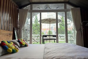 A bedroom with a large bed, a wooden headboard, and a view of an outdoor patio with a table and umbrella. - Nha Cua Bot – 5BR 4BA in DaLat (Dalat)