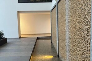A modern indoor space with a tiled floor, a glass railing, and a textured wall. - Setia sky 88 Foo homestay (Johor Bahru)