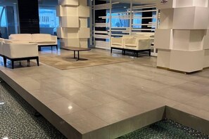 A modern lobby with a tiled floor, white sofas, and a small round table. - Setia sky 88 Foo homestay (Johor Bahru)