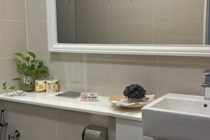 A bathroom with a white sink, a mirror, a window, and a shelf with toiletries and a plant. - Setia sky 88 Foo homestay (Johor Bahru)