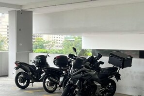 A parking area with motorcycles and a black storage box. - Setia sky 88 Foo homestay (Johor Bahru)
