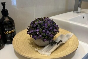 A bathroom with a bathtub, a bottle of shampoo, a potted plant, and a towel on a round tray. - Setia sky 88 Foo homestay (Johor Bahru)