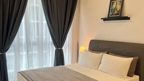 A hotel room with a bed, curtains, a nightstand, a lamp, and a picture on the wall. - Setia sky 88 Foo homestay (Johor Bahru)