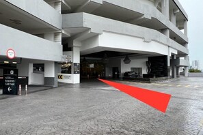 A multi-level parking garage entrance with a red arrow indicating direction, a sign for a resident's parking area, and a building entrance with a staircase. - Setia sky 88 Foo homestay (Johor Bahru)