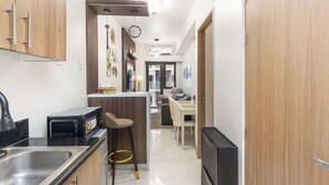 A modern kitchen with a built-in microwave, a sink, and a bar stool. - Shore 3 Residences Tower 2, Lap Pool and Amenities (Pasay)
