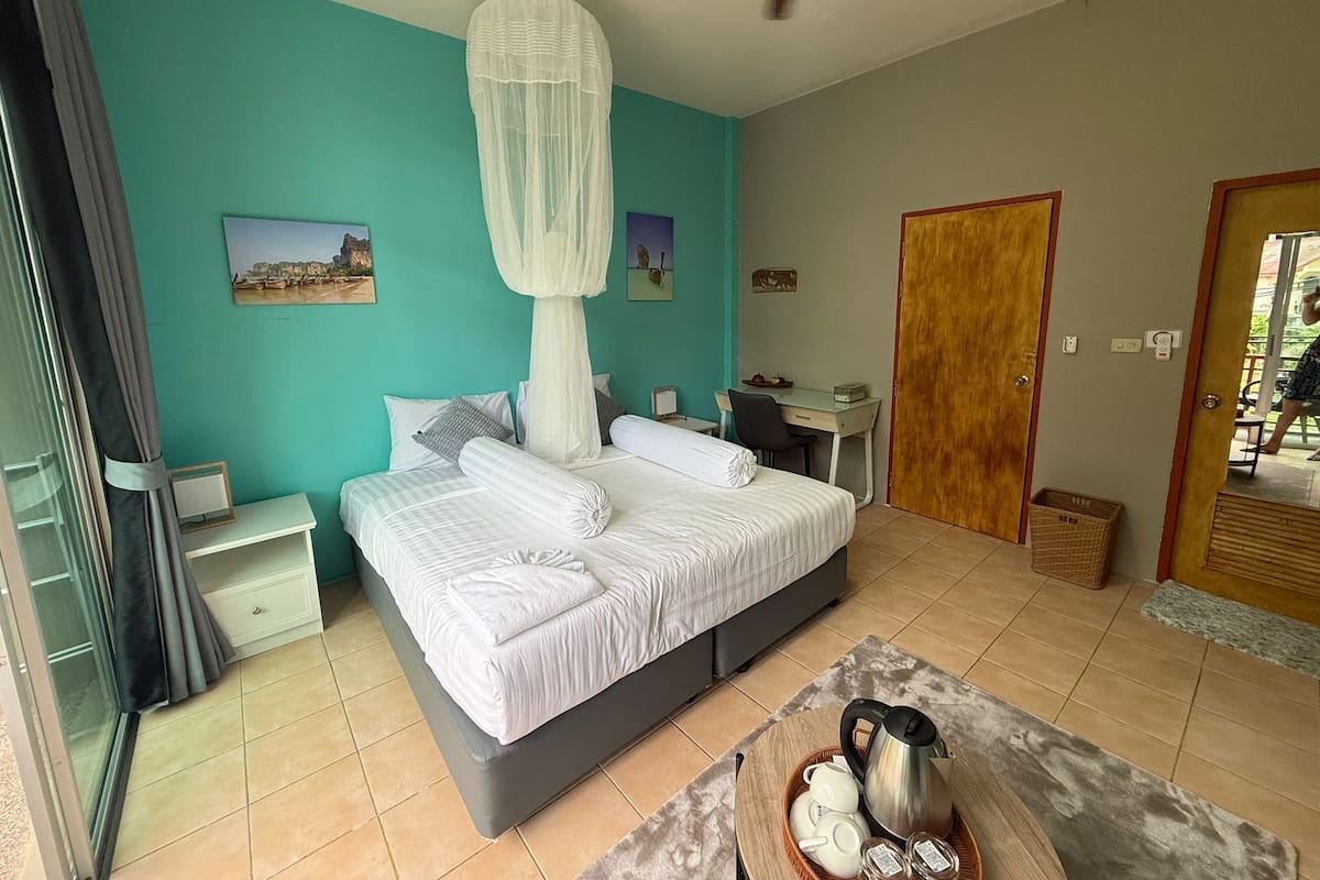 Une chambre à coucher comprenant un lit, un bureau, une chaise, un ventilateur de plafond et une porte.