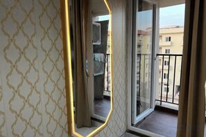 A room with a patterned wall, a sliding glass door leading to a balcony, and a view of buildings outside. - Golden Punjabi House (Zirakpur)