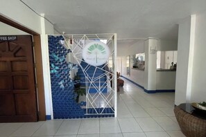 A hallway with a coffee shop sign, a decorative blue and white wall, and a door.
