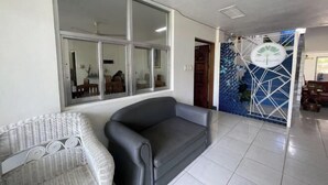 Een kamer met een groot raam, een zwarte bank en een gestreept fauteuil.