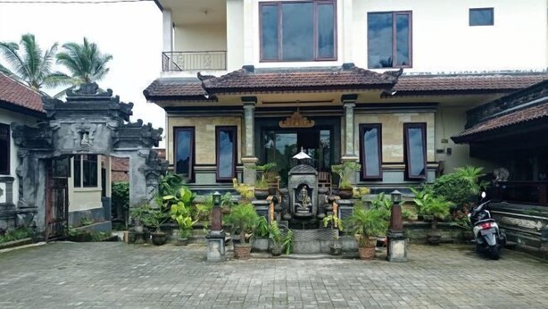 A traditional house with a central shrine, potted plants, and a parked motorcycle. - Hotel Mawar Sari Mitra RedDoorz (Bali)