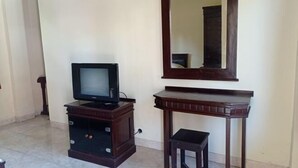 A room with a television on a wooden cabinet, a mirror above it, and a small stool. - Hotel Mawar Sari Mitra RedDoorz (Bali)
