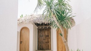 A traditional wooden door with a thatched roof entrance, flanked by two arched doorways, leading to a stone-paved area. - X Villa Khana · Exquisite 3br villa Canggu (Bali)