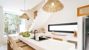 A modern kitchen with a large island, white cabinetry, and a large window providing natural light. - X Villa Khana · Exquisite 3br villa Canggu (Bali)