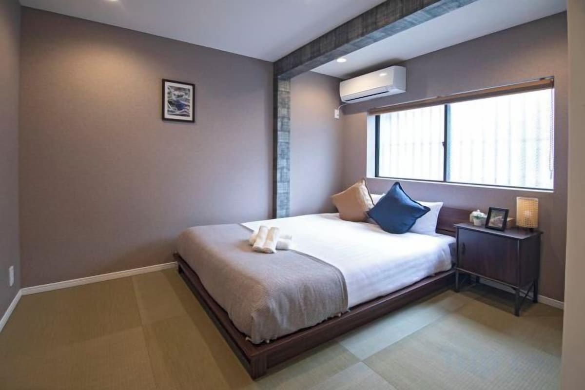 A bedroom with a bed, bedside table, and a window.
