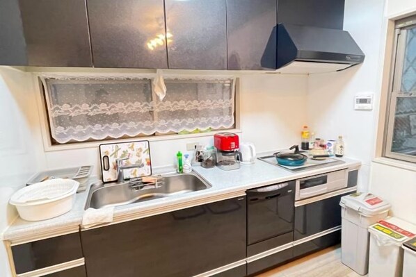A kitchen with a sink, stove, and cabinets. - Peacock (Osaka)