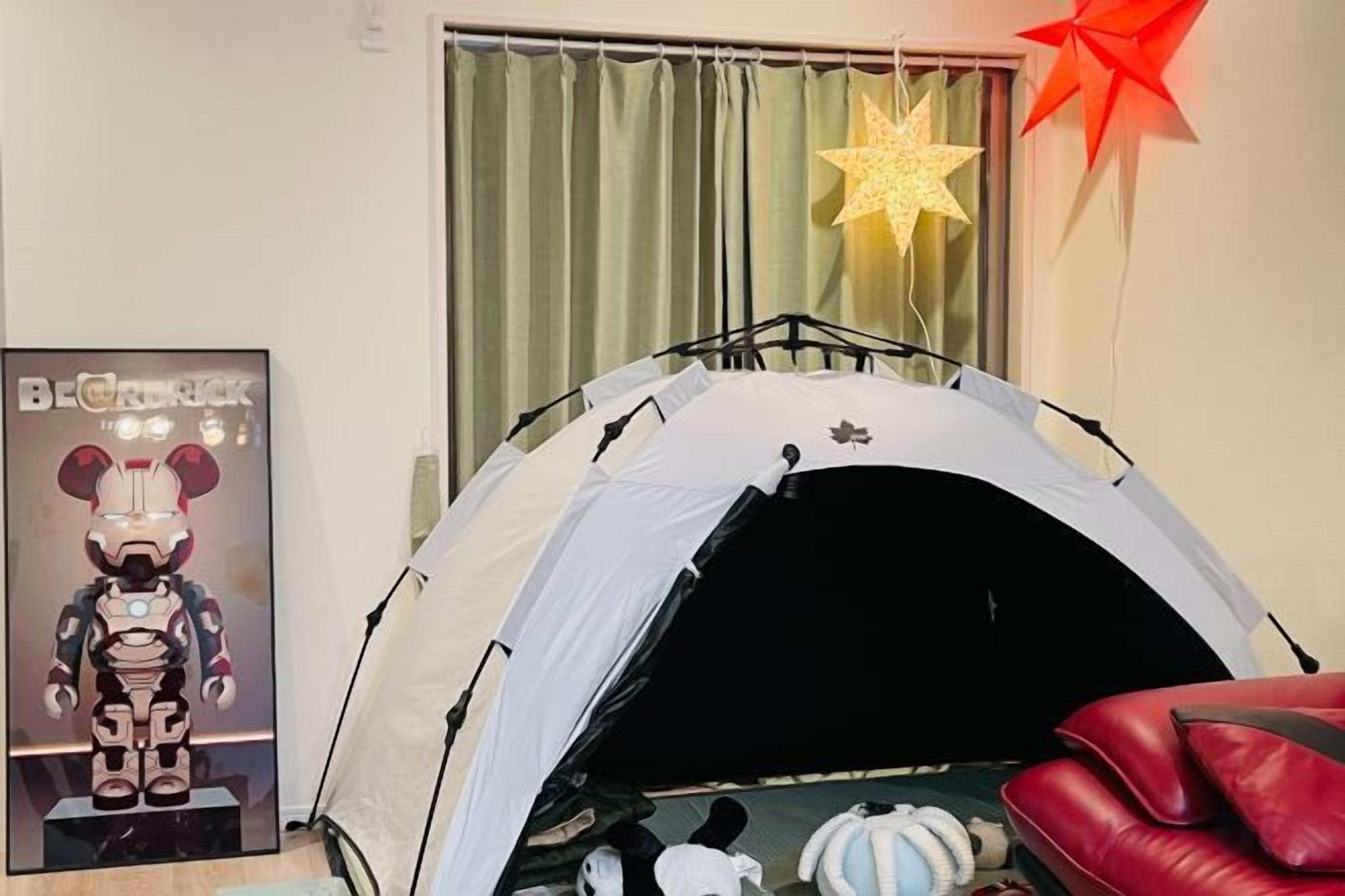 A tent-like structure in a room with a poster, a star decoration, and a red chair.