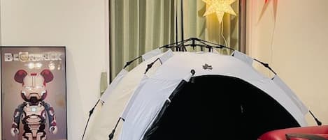 A tent-like structure in a room with a poster, a star decoration, and a red chair.