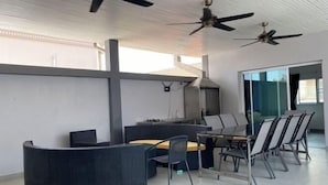 A modern indoor space with a curved seating area, a dining table with chairs, and ceiling fans. - south pattaya soi adam 5 bedrooms pool villa (Pattaya)
