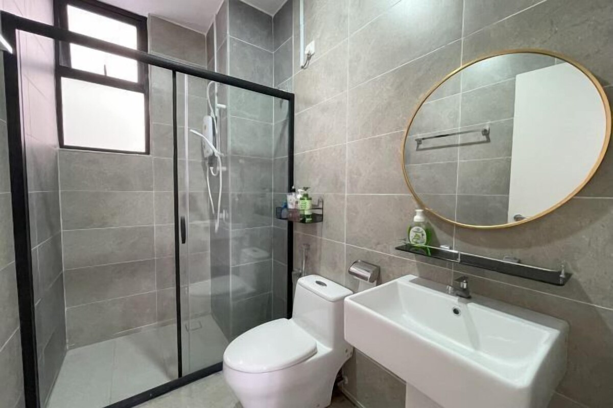 Une salle de bain dotée d’une douche à parois de verre, de toilettes, d’un lavabo et d’un miroir avec un cadre doré.