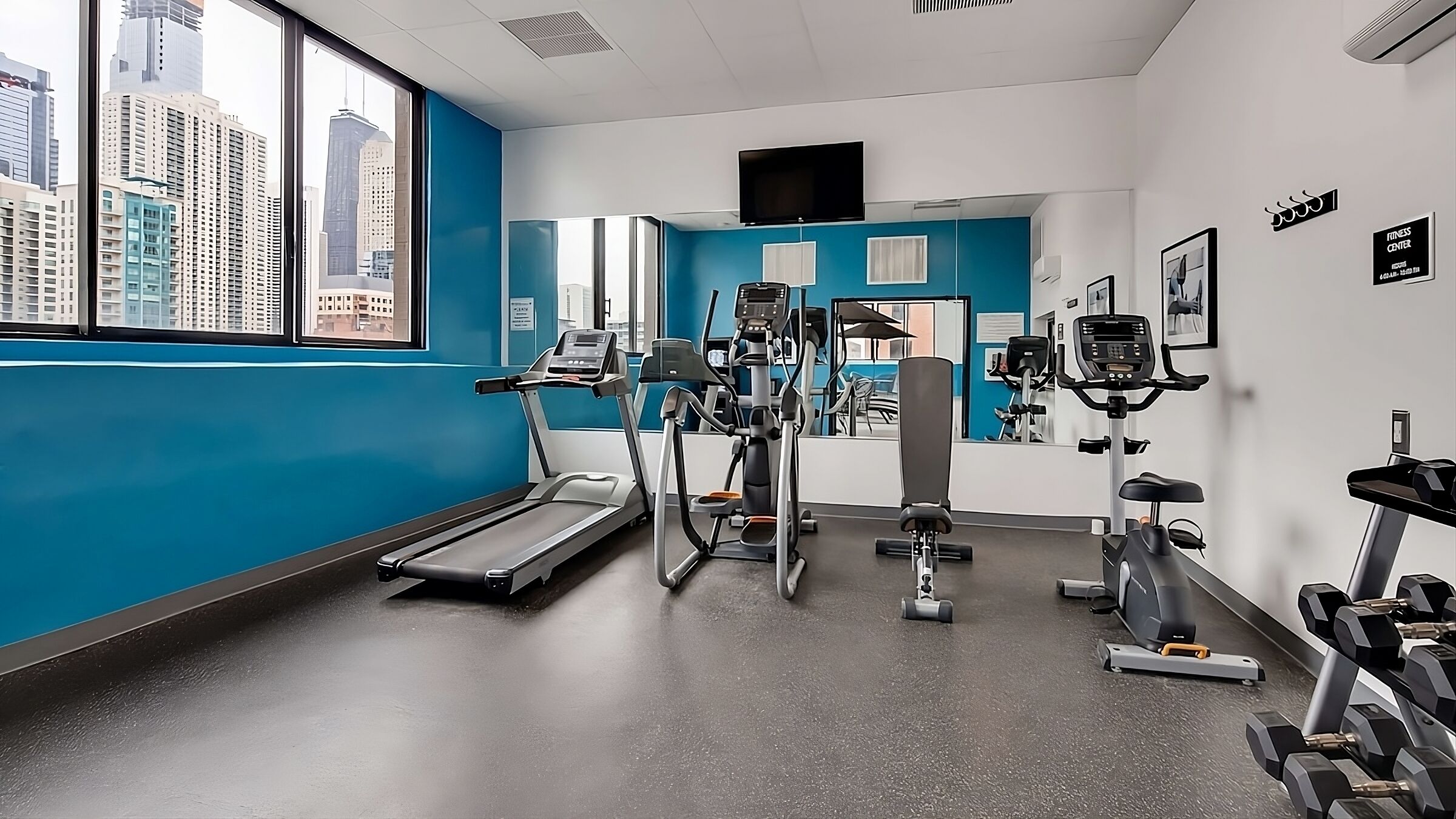 A gym with treadmills, elliptical machines, and dumbbells.
