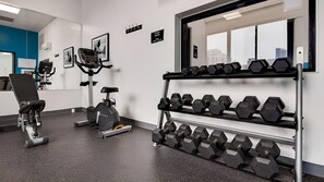 A gym with exercise equipment, including a stationary bike, a rowing machine, and a rack of dumbbells. - Group Vacation! 4 Comfortable Units (Chicago)