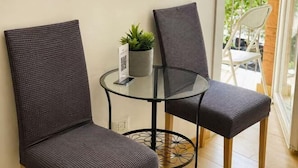 A small glass table with two wicker chairs, a potted plant, and a QR code sign. - huaxia (Venice)