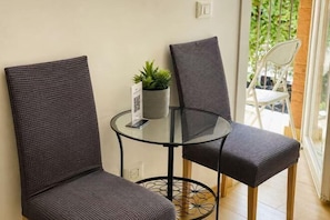 A small glass table with two wicker chairs, a potted plant, and a QR code sign. - huaxia (Venice)