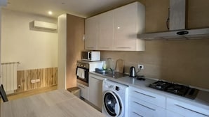 A compact kitchen with a washing machine, microwave, and stove. - huaxia (Venice)