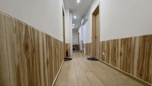 A hallway with wooden paneling, a tiled floor, and doors on both sides. - huaxia (Venice)