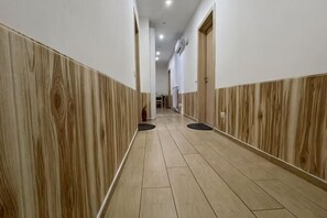 A hallway with wooden paneling, a tiled floor, and doors on both sides. - huaxia (Venice)