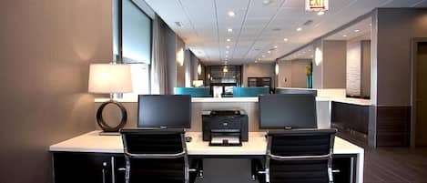 A modern hotel lobby with two desks, a reception area, and an exit sign.