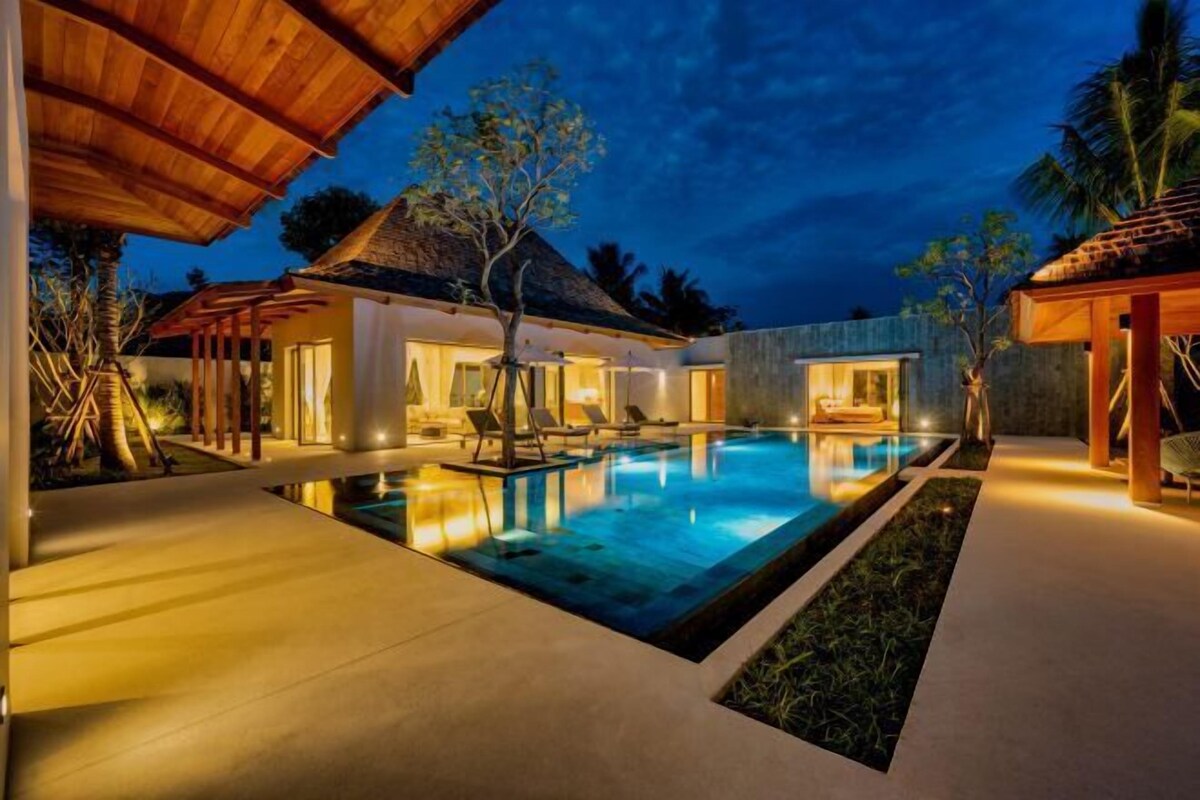 A modern resort with a swimming pool, lounge chairs, and a covered area.