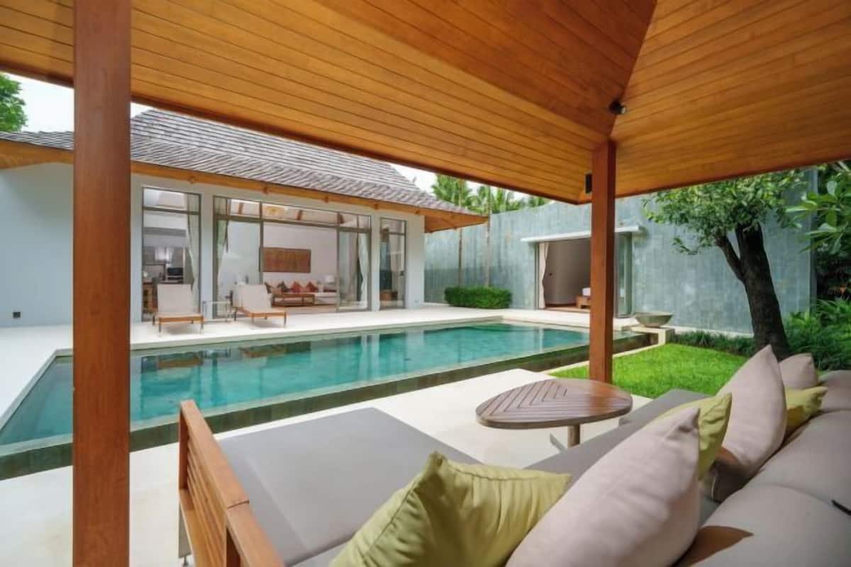 Ein moderner Poolbereich im Freien mit Liegestühlen und einer Holzpergola.