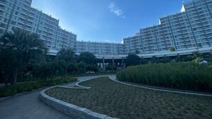 Ein modernes Hotel mit mehreren Hochhäusern, einem angelegten Garten und blauem Himmel.