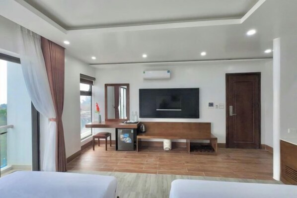 A hotel room with a bed, a desk, a TV, and a window with curtains.