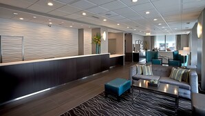 Eine moderne Lobby mit Rezeption, Sitzgelegenheiten und Blick auf die Küche.
