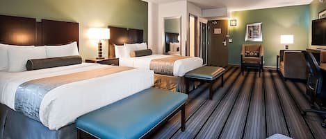 A hotel room with two beds, a bench, a desk, and a chair.