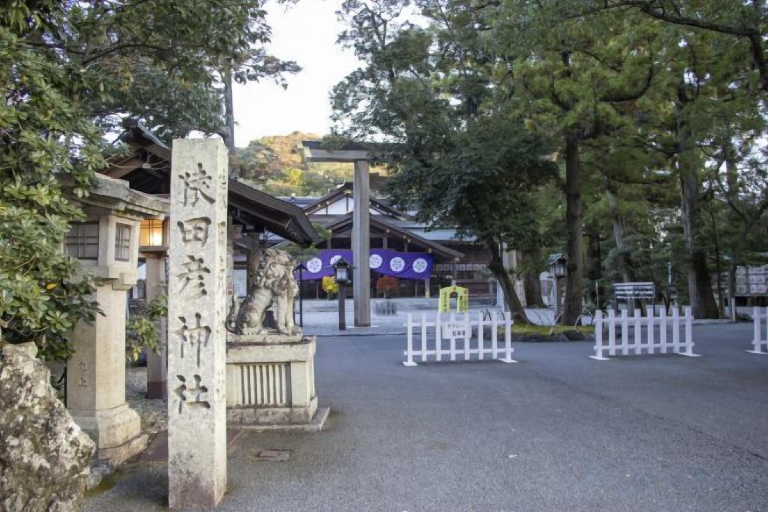 Un torii tradicional japonés con pilares de piedra y una estructura de madera al fondo.