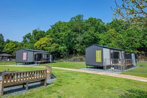 A campsite with two cabins, a picnic table, and a wooden bench.